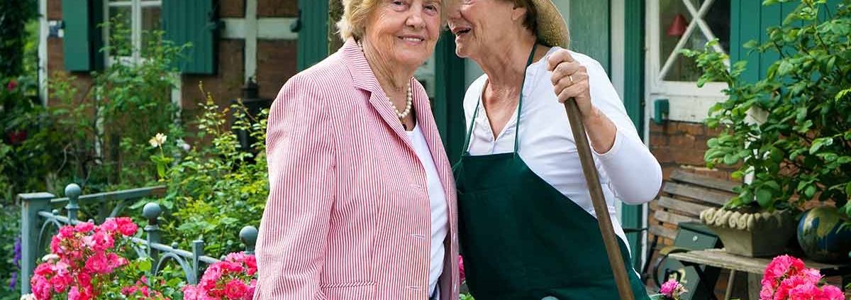 Zwei Nachbarinnen stehen am Zaun und unterhalten sich