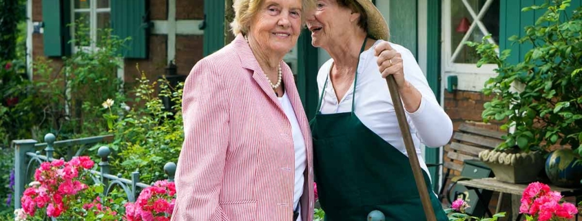 Zwei Nachbarinnen stehen am Zaun und unterhalten sich