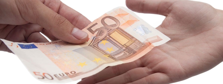 Großansicht zweier Hände: Eine Person überreicht der anderen Geld