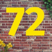 Auf einer Mauer aus roten Backsteinen steht 72, oben rechts wächst Efeu und links stehen Osterglocken | Wohnträume der Deutschen