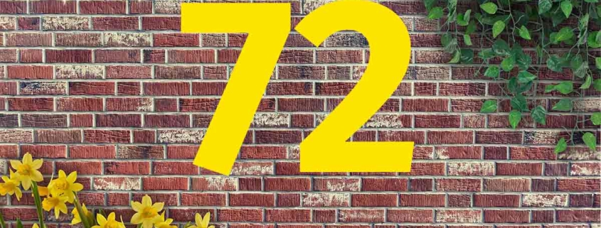 Auf einer Mauer aus roten Backsteinen steht 72, oben rechts wächst Efeu und links stehen Osterglocken | Wohnträume der Deutschen