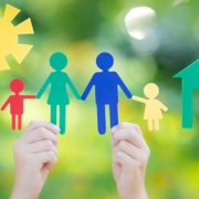 Vier Kinderhände halten bunte Familie aus Papier in die Luft vor unscharfen grünen Bäumen - Immobiliensuche -