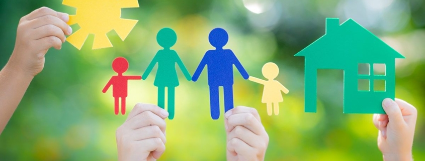 Vier Kinderhände halten bunte Familie aus Papier in die Luft vor unscharfen grünen Bäumen - Immobiliensuche -