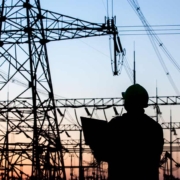 Ein Mann vor Strommasten im Sonnenuntergang - Strompreise- lohnt sich der Wechsel
