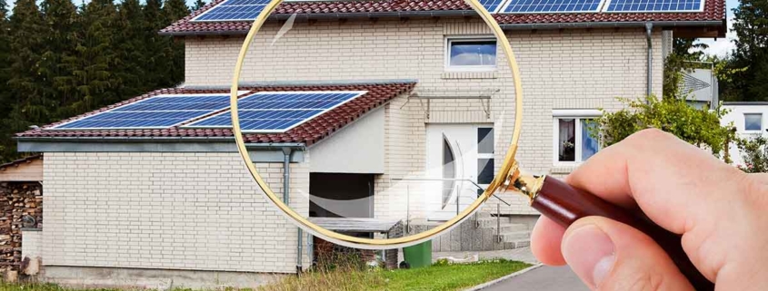 Eine Hand mit Lupe vor einem Haus mit Garage - Suchauftrag