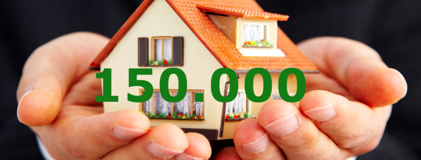 Ein paar Hände halten ein Spielzeughaus mit der Zahl 150000 - Kfw Zuschuss