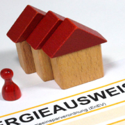 Drei Spielzeughäuser und eine Figur und ein Energieausweis - Sanierungspflicht EU