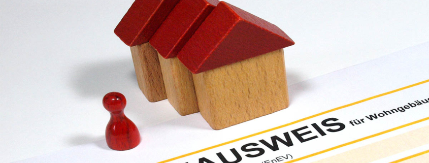 Drei Spielzeughäuser und eine Figur und ein Energieausweis - Sanierungspflicht EU