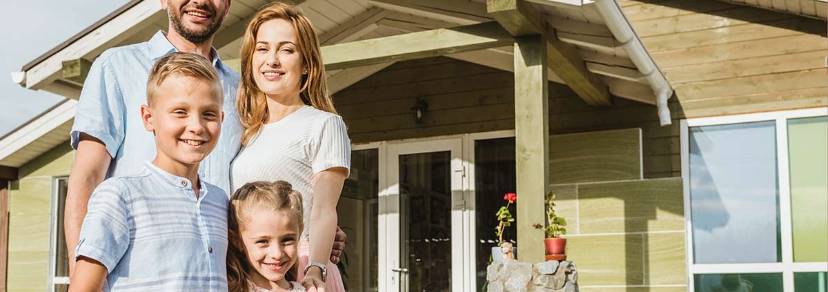 Glückliche Familie vor Effizienzhaus 40, das vom Staat gefördert wurde.