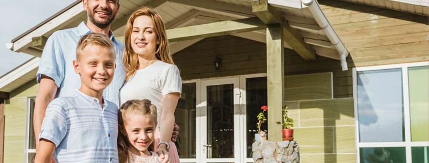 Glückliche Familie vor Effizienzhaus 40, das vom Staat gefördert wurde.