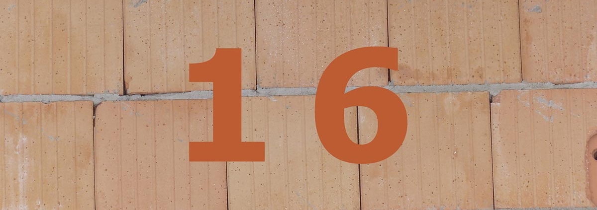 Orange Zahl 16 auf gemauerter Häuserwand.