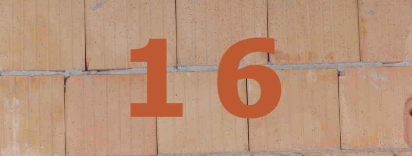 Orange Zahl 16 auf gemauerter Häuserwand.