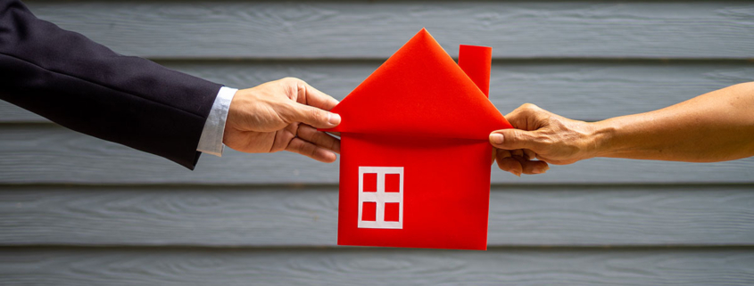 Mann und Frau ziehen an einem roten Haus aus Stoff | Scheidung