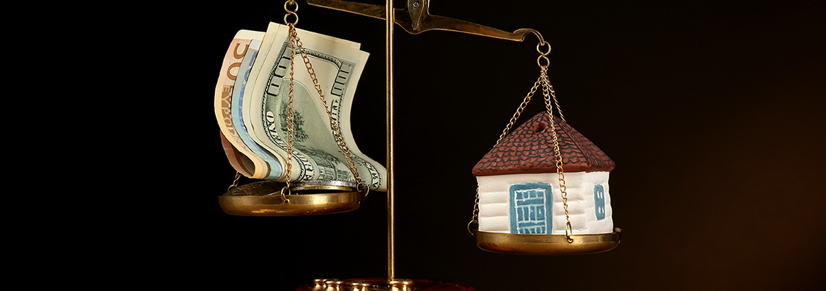 Scale with money and model of house on dark background; Wertermittlung