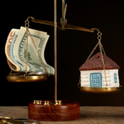 Scale with money and model of house on dark background; Wertermittlung
