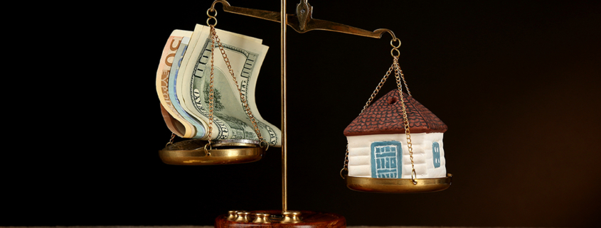 Scale with money and model of house on dark background; Wertermittlung