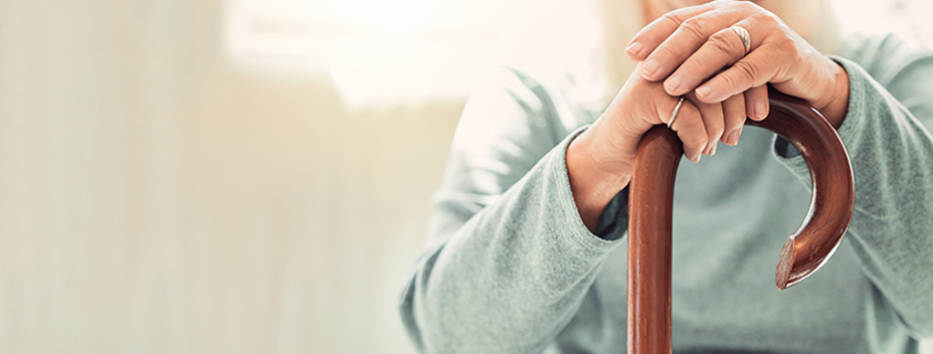 Growing old is inevitable, but growing up is optional. elderly woman resting her hands on her walking stick while relaxing at home; Wohnen im Alter
