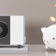 Vor einer braunen Wand steht links eine Wärmepumpe, rechts steht ein Sparschwein auf einem Bein, dem vorderen linken, die anderen Beine schweben in der Luft, von oben Fallen Goldmünzen in das Sparschwein | Energetische Sanierung