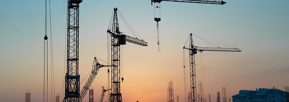 Baukräne für Wohngebäude in einer Stadt bei Sonnenuntergang | Neubau oder Bestandsimmobilie