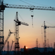 Baukräne für Wohngebäude in einer Stadt bei Sonnenuntergang | Neubau oder Bestandsimmobilie