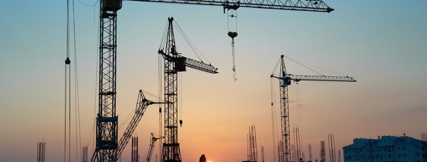 Baukräne für Wohngebäude in einer Stadt bei Sonnenuntergang | Neubau oder Bestandsimmobilie